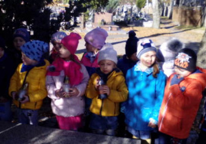 Grupa dzieci stojąca przy grobie żołnierzy.
